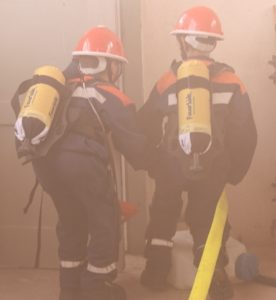 Zwei Mitglieder der Jugendfeuerwehr mit Atemschutzbehältergeräten Atrappen in einen vernebelten Raum